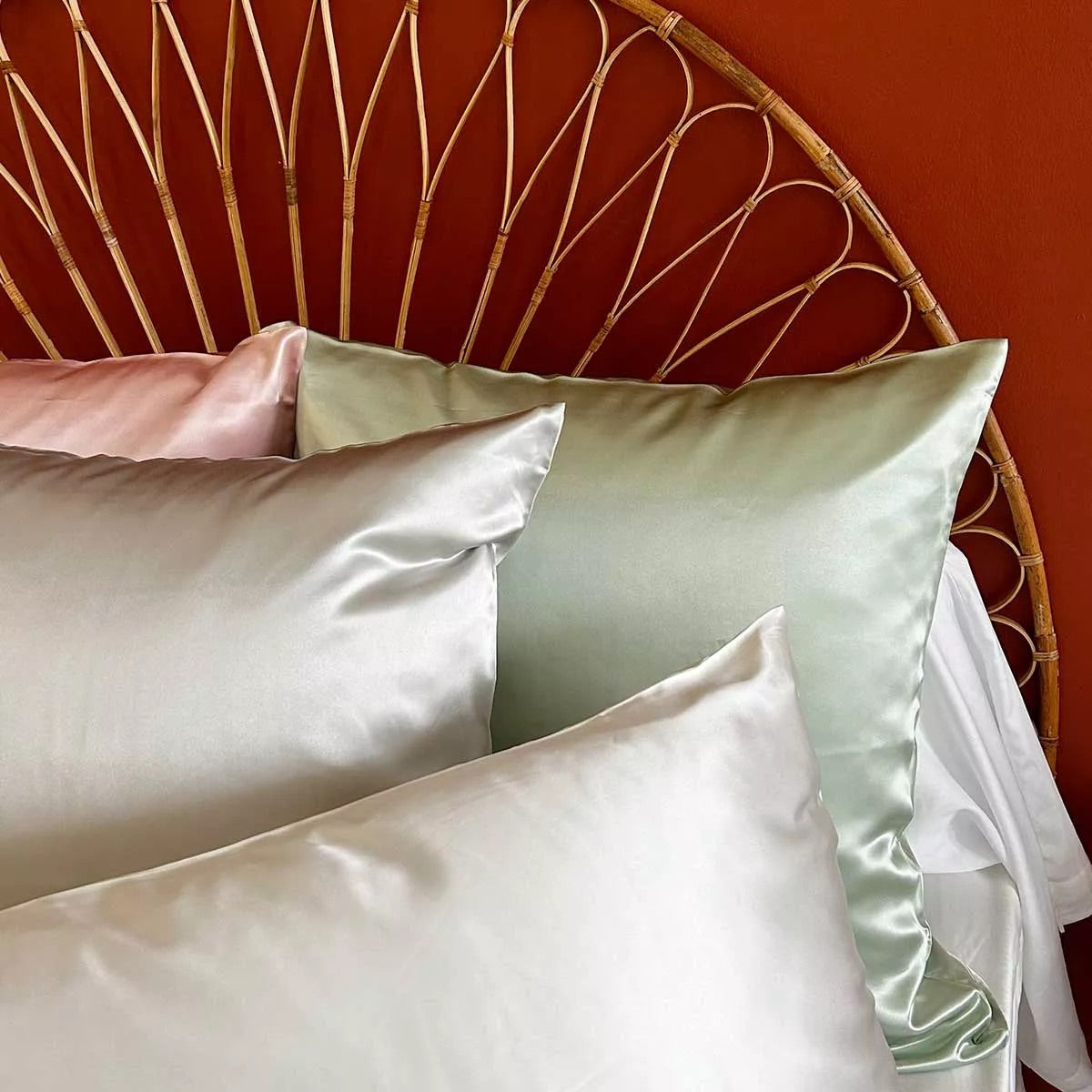 Taies d'oreiller en soie parfumées sur une tête de lit en rotin