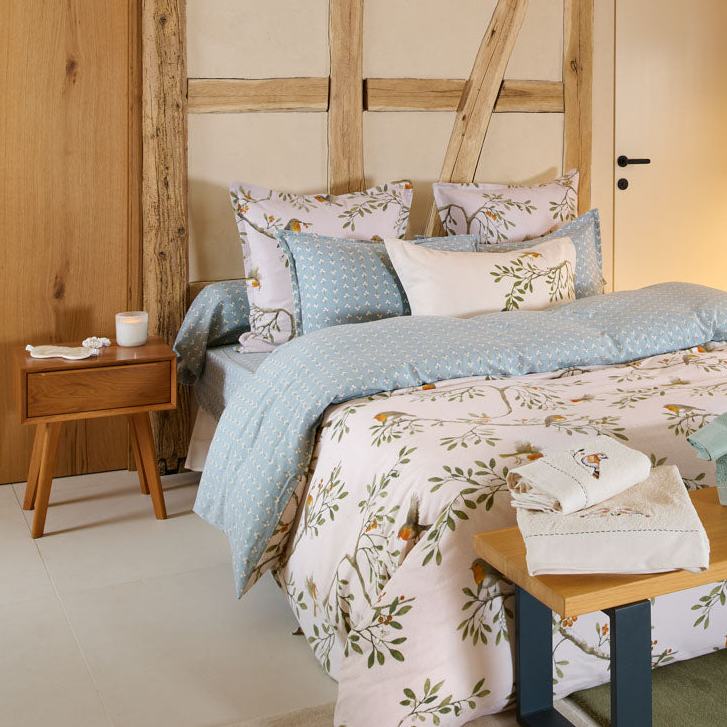 Drap-housse Doux Refuge en flanelle de coton 160 g/m², imprimé petites fleurs blanches sur fond vert céladon, coordonné à la parure de lit aux motifs d'oiseaux et de feuillages.
