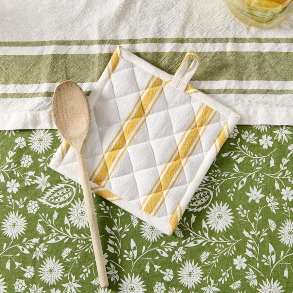 manique verte et gant de cuisine sur nappe fleurie