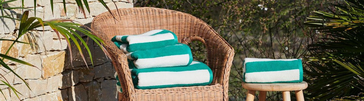 Serviettes de bain rayées vertes sur un fauteuil en rotin