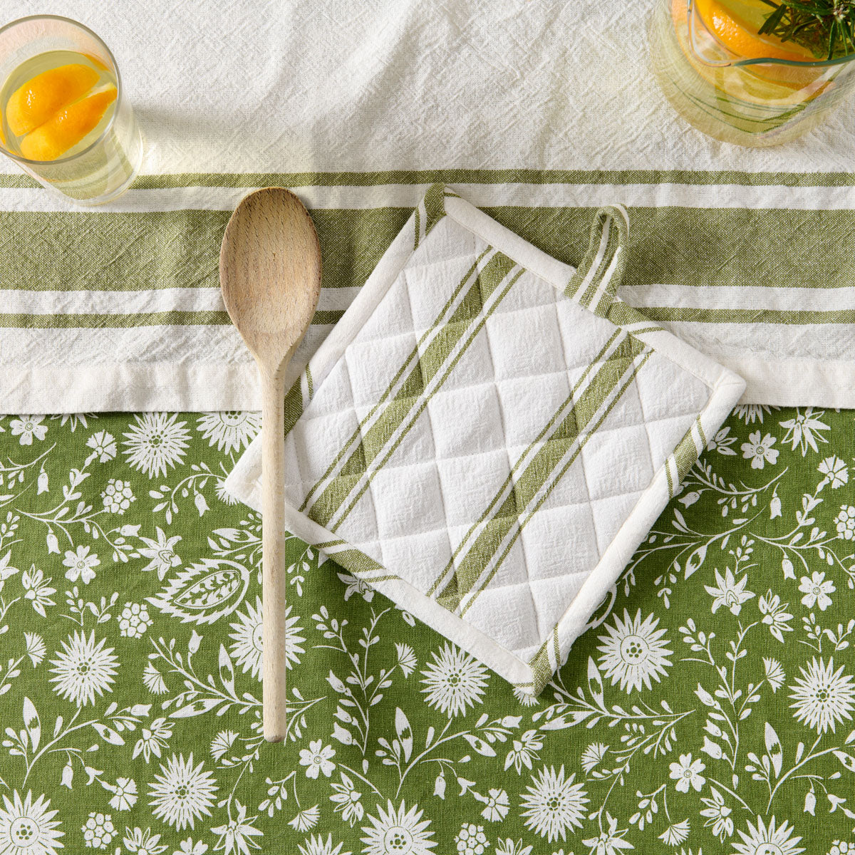 manique verte et cuillère en bois sur nappe fleurie #Couleur_VERT