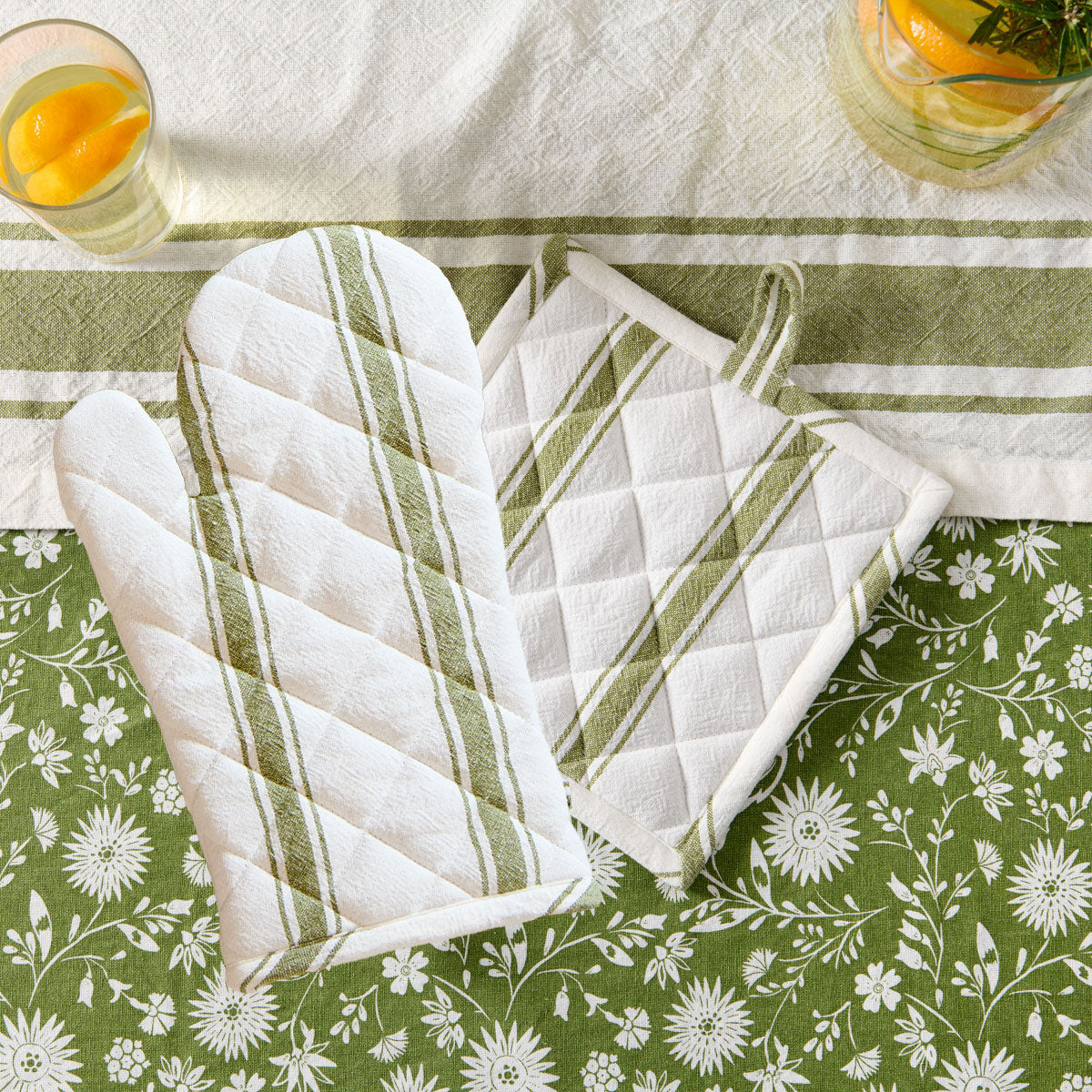 manique verte et gant de cuisine sur nappe fleurie #Couleur_VERT