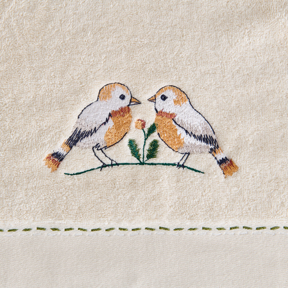 Détail de la broderie oiseau sur le drap de bain Doux Refuge et finition mini-liteau