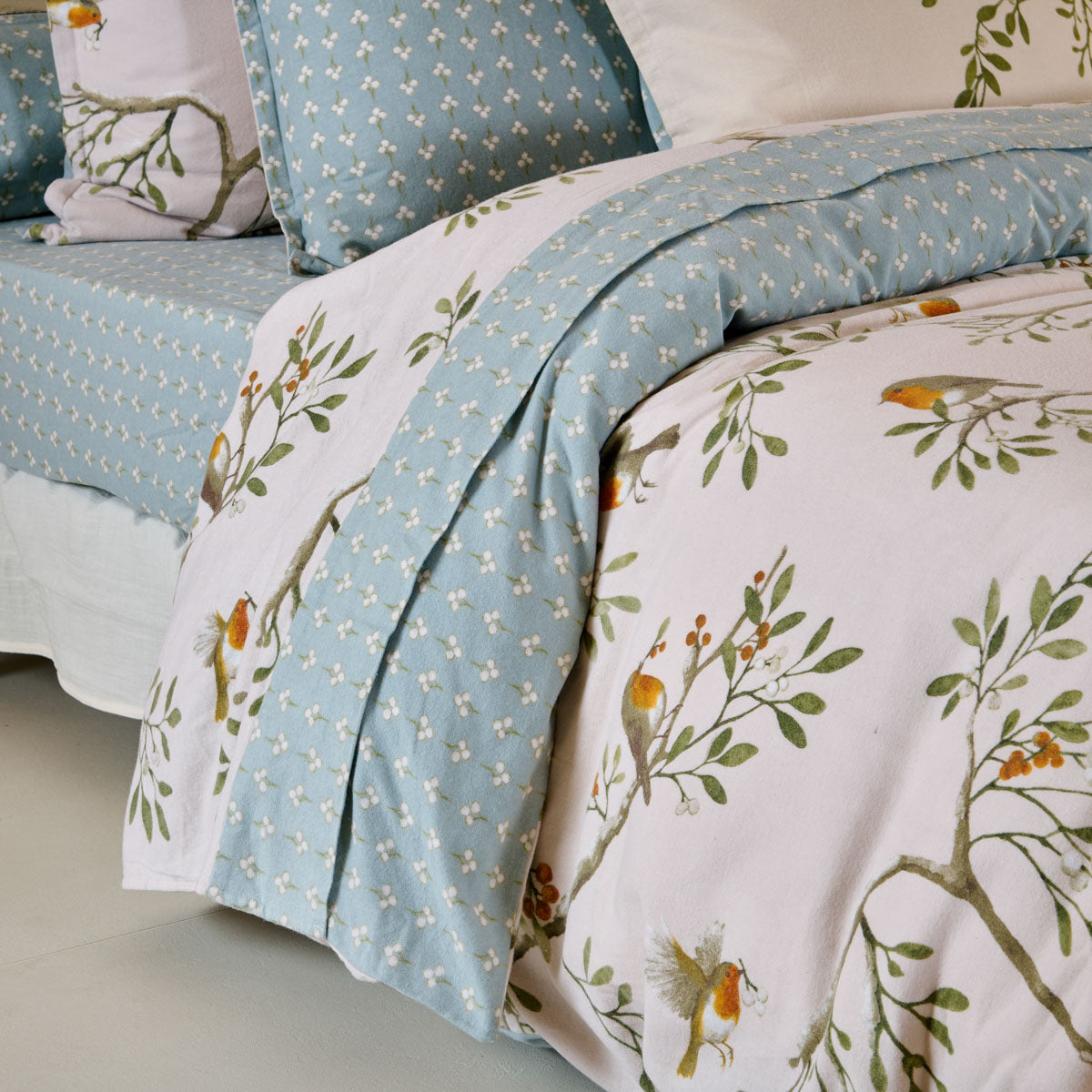 Drap plat Doux Refuge en flanelle de coton 160 g/m², imprimé oiseaux et feuillages, avec parement floral vert céladon de 20 cm.